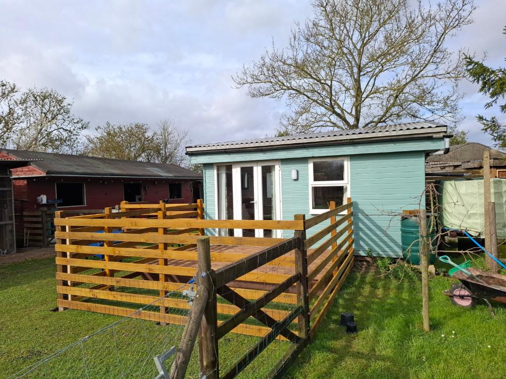 a small blue house with a wooden fence at Mardi Gras, Upwell in Upwell