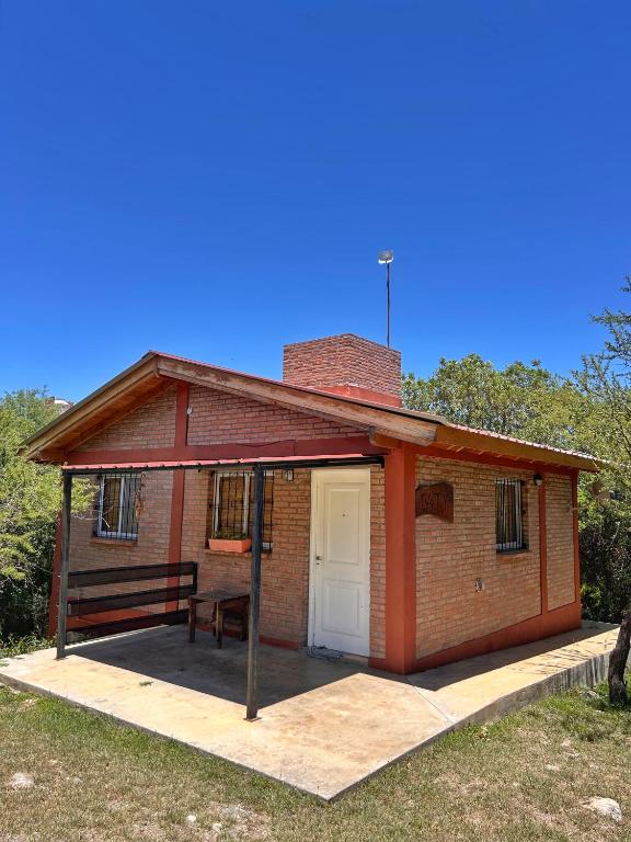 a small brick house with a porch and a white door at Caty in Merlo