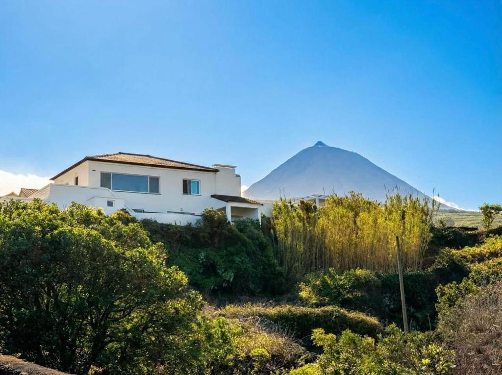 a house in the foreground with a mountain in the background at Pico Island Villas 38 - Private Atlantic Retreat in Santo António