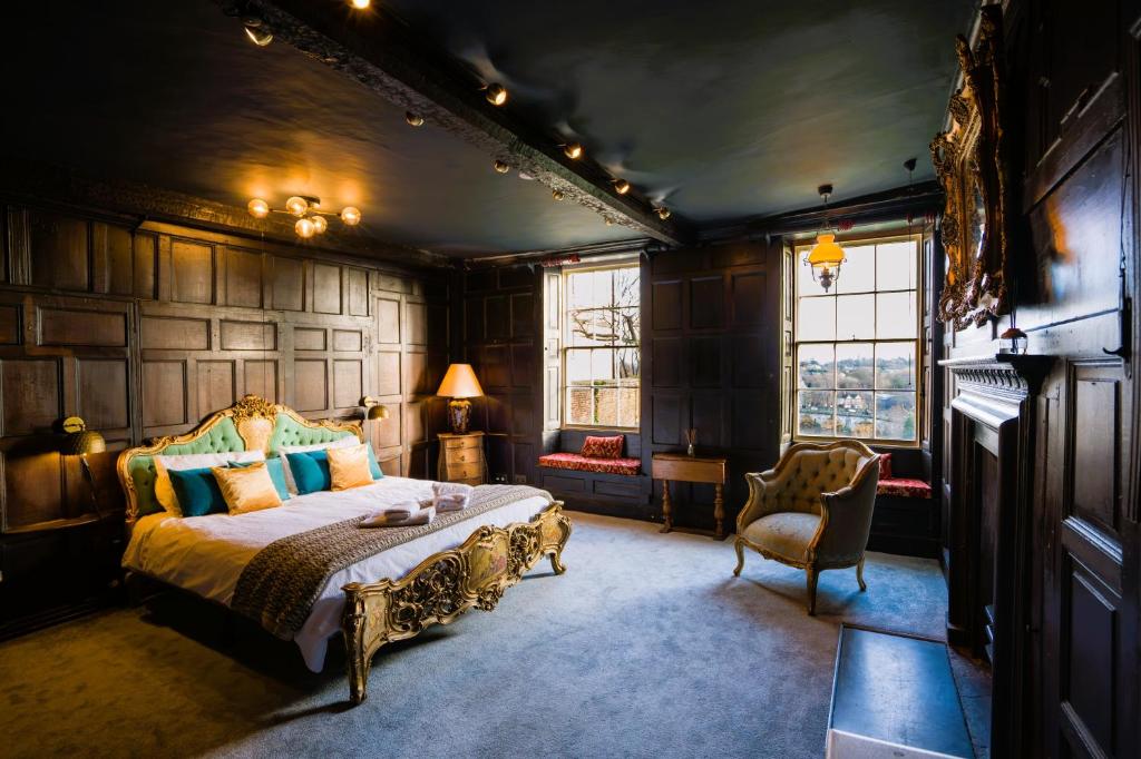 a bedroom with a bed and a chair and windows at The Old House Apartment in Shrewsbury