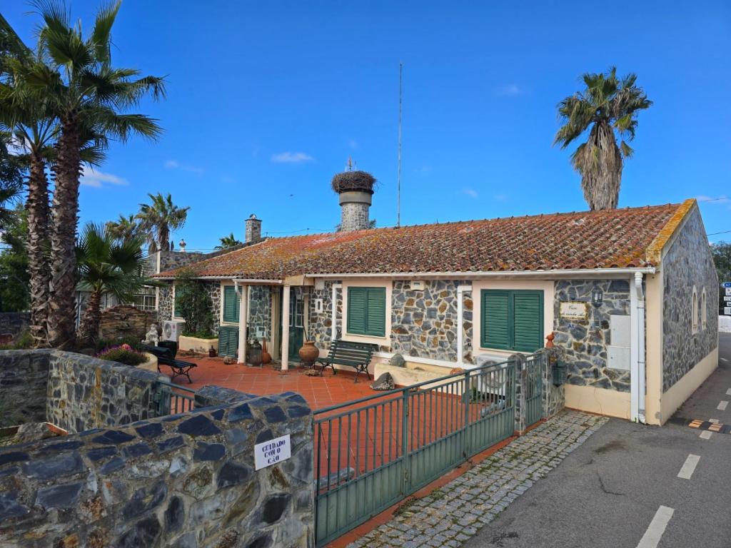 a stone house with green shutters and palm trees at Casa da Minha Avó in São Pedro de Solis
