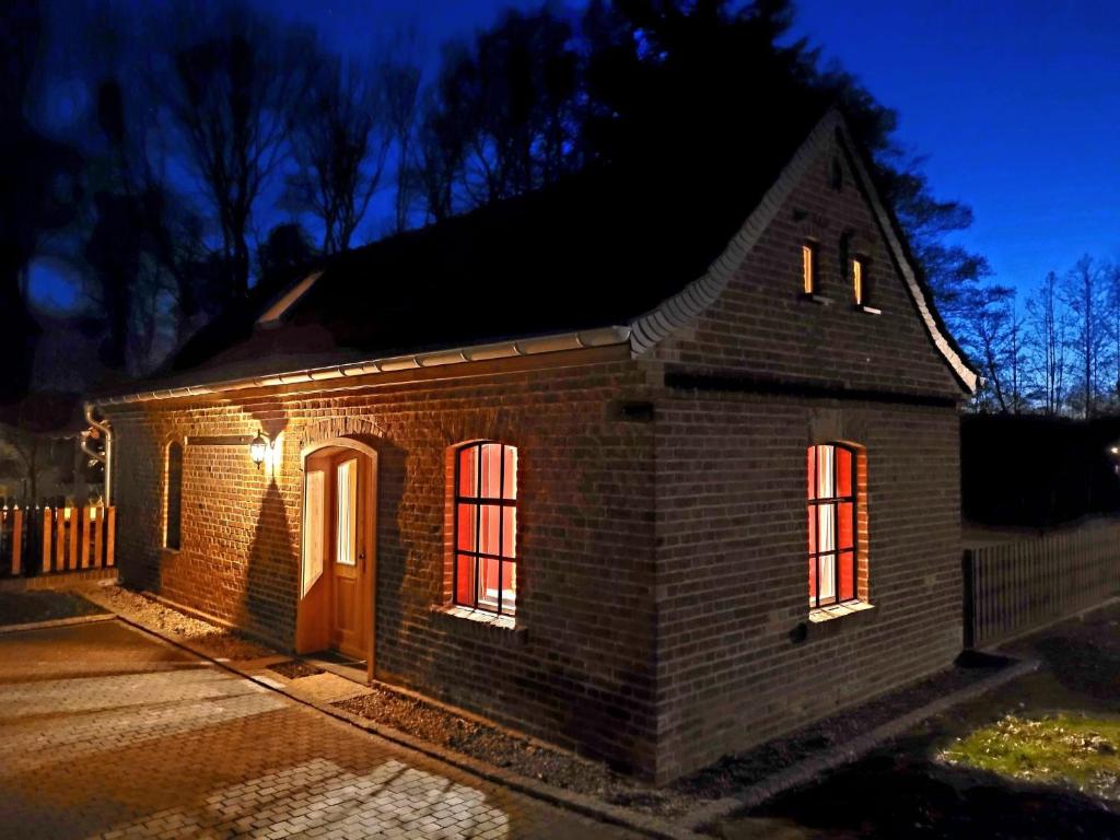 a brick house with lights in the windows at night at Alte Schmiede in Schwielochsee