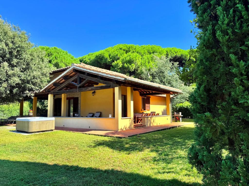 a small yellow house in a field with a yard at Ville Di Villa Biserno in San Vincenzo