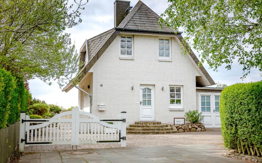 a white fence in front of a white house at Ferienhaus Weitblick in Morsum
