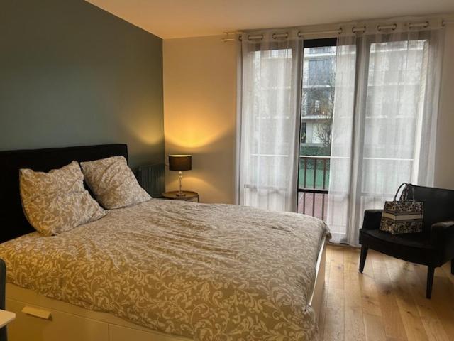 a bedroom with a bed and a large window at STUDIO PROCHE PARIS VERSAILLES in Villennes-sur-Seine