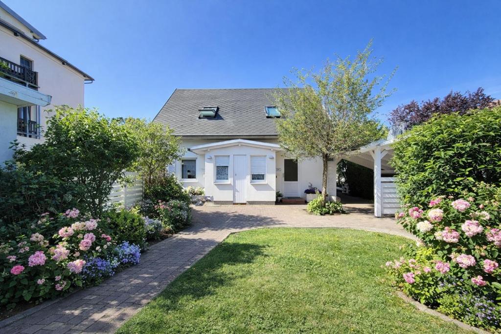 a white house with a yard with flowers at Fewo Lee in Kühlungsborn