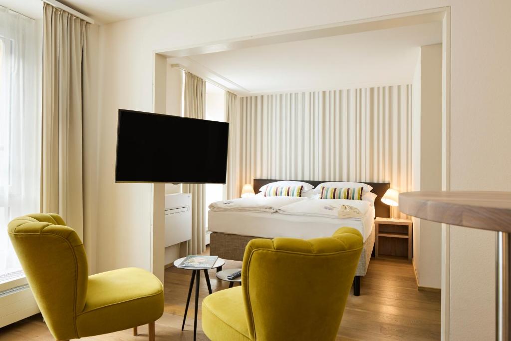 a hotel room with a bed and two chairs at PLATZHIRSCH ZÜRICH - Downtown Boutique Hotel & Sushi Lounge in Zurich