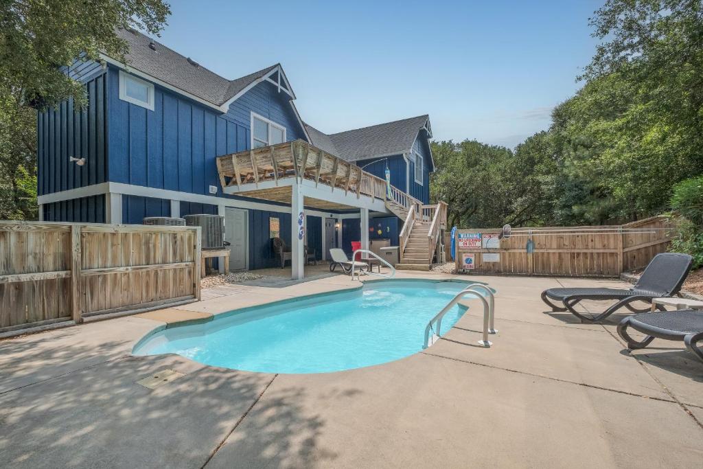 a swimming pool in front of a blue house at 4620 - Flip Flop Inn in Southern Shores