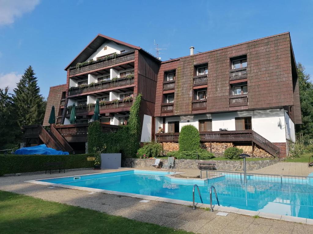 an apartment building with a swimming pool in front of it at Hotel Pavla Vysočina in Nové Město na Moravě