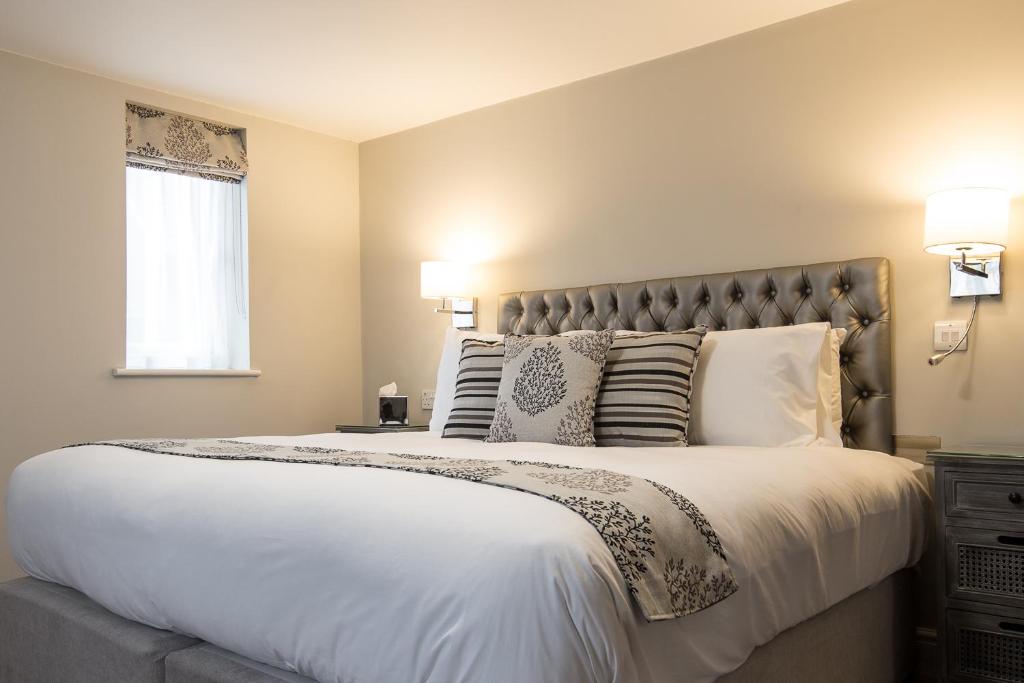 1 dormitorio con 1 cama grande con sábanas y almohadas blancas en The Maple Manor Hotel and guest holiday parking, en Crawley