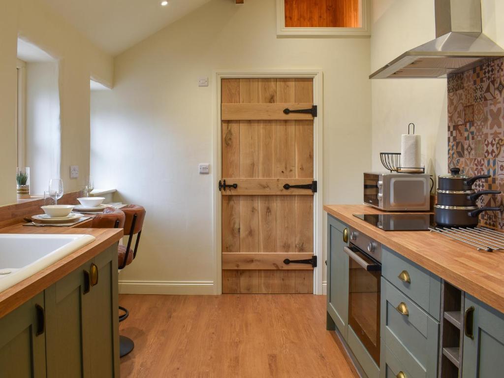 a kitchen with a sink and a stove top oven at The Cowshed - Uk50283 in Earl Sterndale