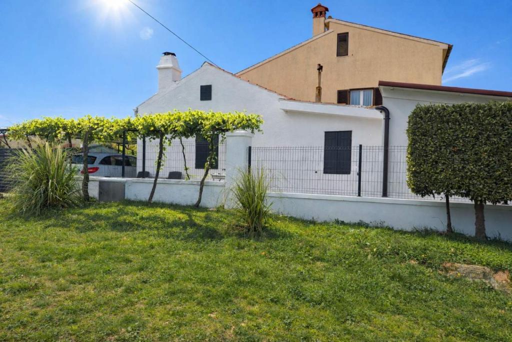 a white house with a fence in a yard at Solmar Adriatica Apartman in Banjole