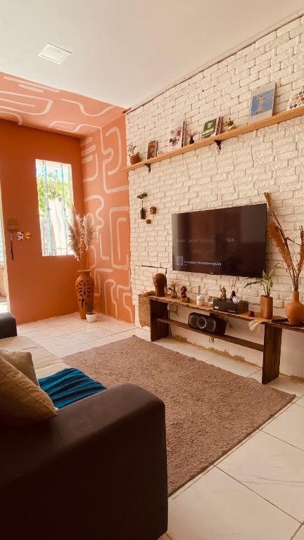 a living room with a flat screen tv on a brick wall at Bossa Nova Home in Barra dos Coqueiros