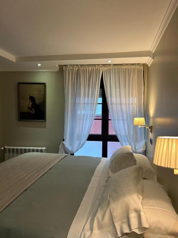 a bedroom with a large white bed with a window at Hotel Arco Navia in Navia