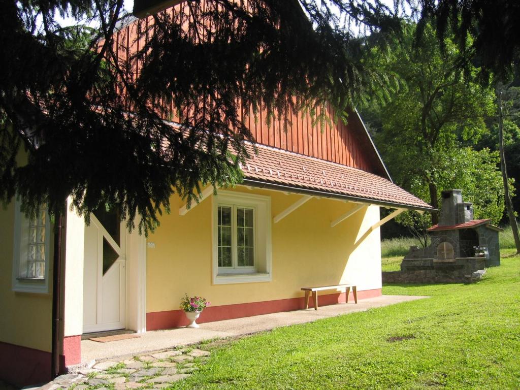 żółto-czerwony budynek z oknem i ławką w obiekcie Apartment Vintgar w mieście Slovenska Bistrica