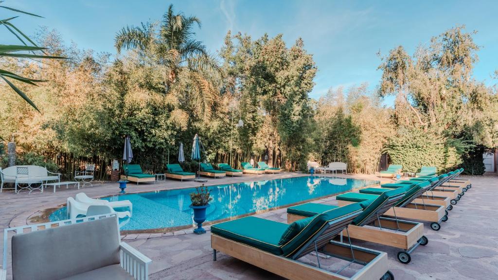 una piscina con sedie a sdraio e alberi di Le Bled Ferme a Marrakech