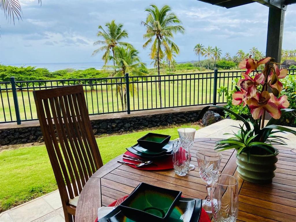 a wooden table with plates and glasses on a balcony at Unit 18 Relaxing Oceanview Studio in Pahala