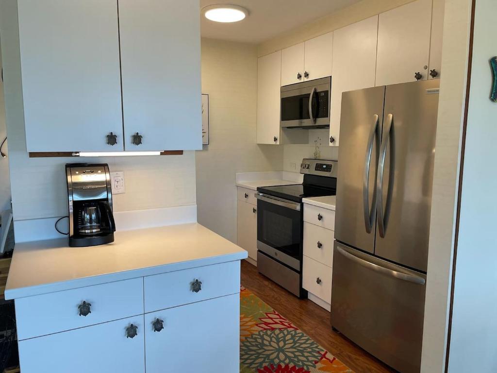 a kitchen with white cabinets and a stainless steel refrigerator at 37 1 Bed 1 Bath with Ocean Views in Pahala