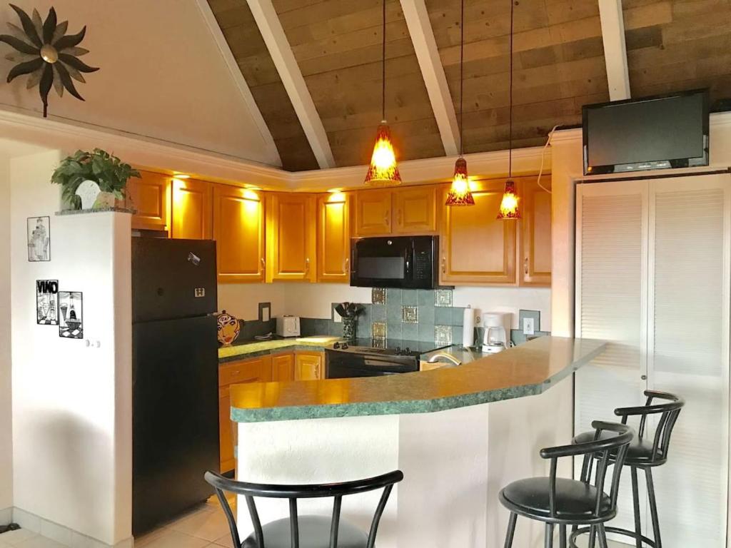 a kitchen with a counter with chairs and a refrigerator at 56 One Bedroom One Bath with Ocean Views in Pahala