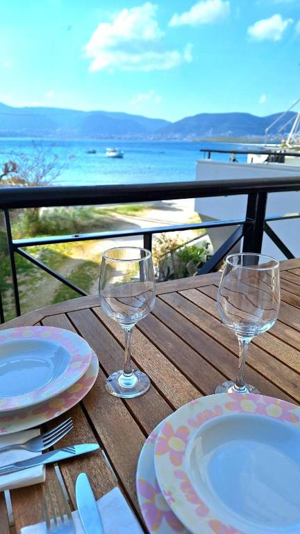 a wooden table with two wine glasses and plates on it at The Beach House in Porto Rafti