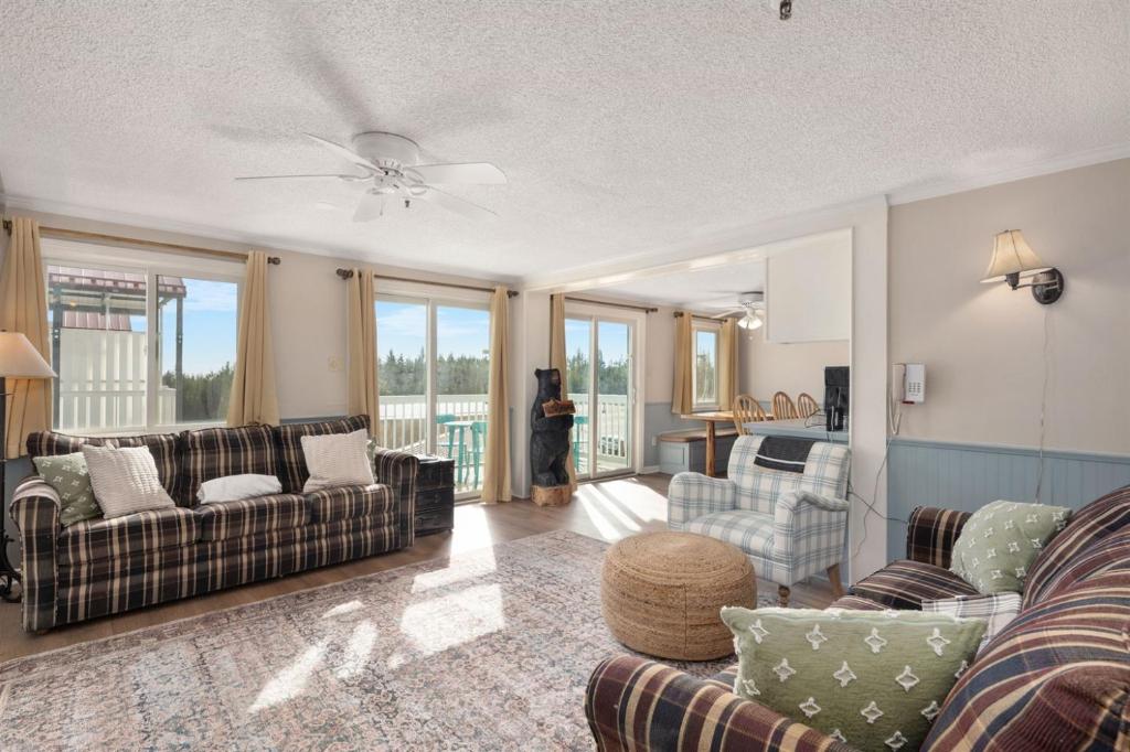 a woman standing in a living room with a couch at Snowshoe Ski-InSki-Out Steps to Ballhooter Lift Mountain Lodge Condo in Snowshoe