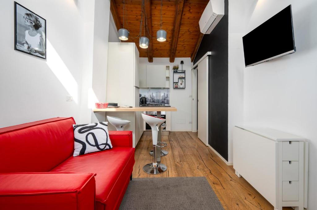 a living room with a red couch and a kitchen at Appartamento Elegante con 2 Camere nel Centro Storico di Bologna in Bologna