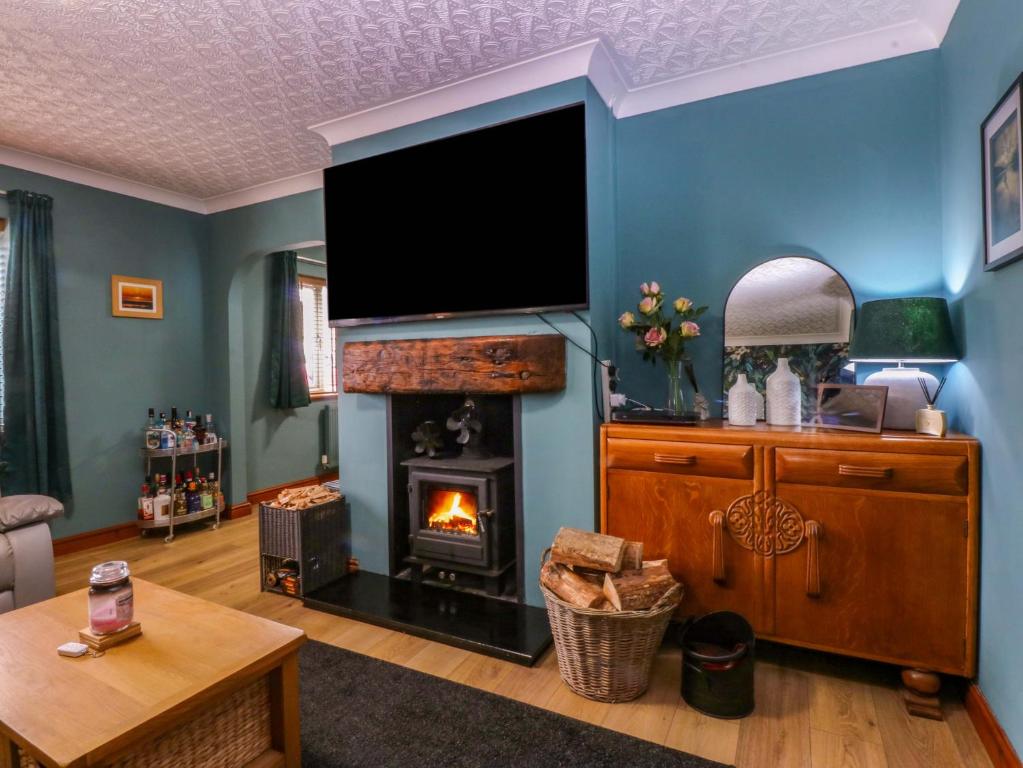 a living room with a fireplace and a flat screen tv at 36 Cae Rhos in Holyhead