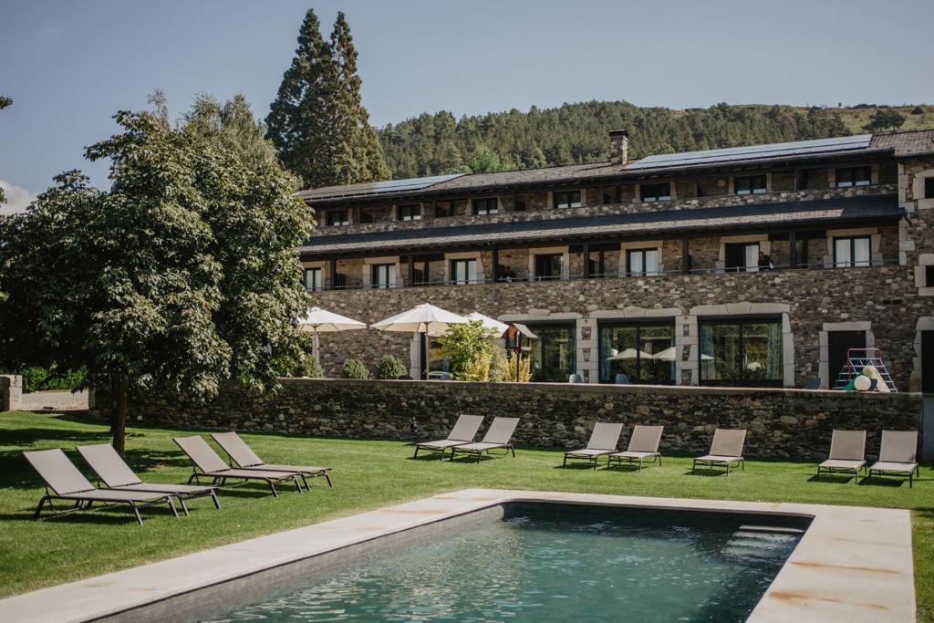 a resort with a swimming pool and chairs and a building at Hotel Bernat de So in Llivia