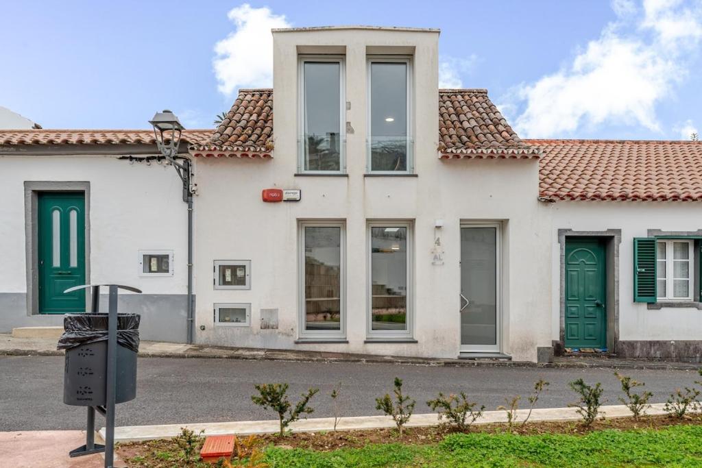 a white house with green doors on a street at Casa da Ponte in Nordeste