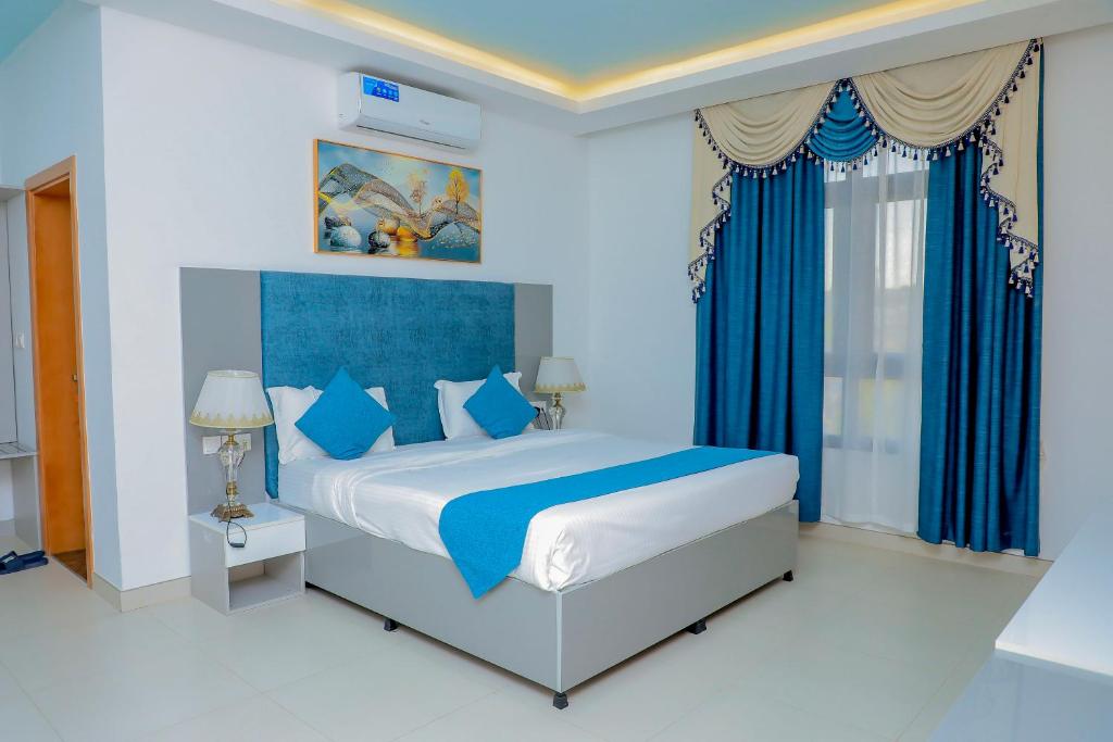 a bedroom with a large bed with blue curtains at Gulf Star Hotel Hargeisa in Hargeysa