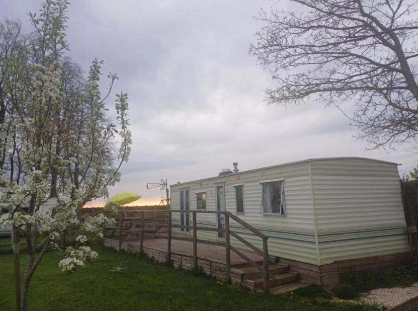 a mobile home with a wooden deck in a yard at L'ancyze in Le Torp-Mesnil