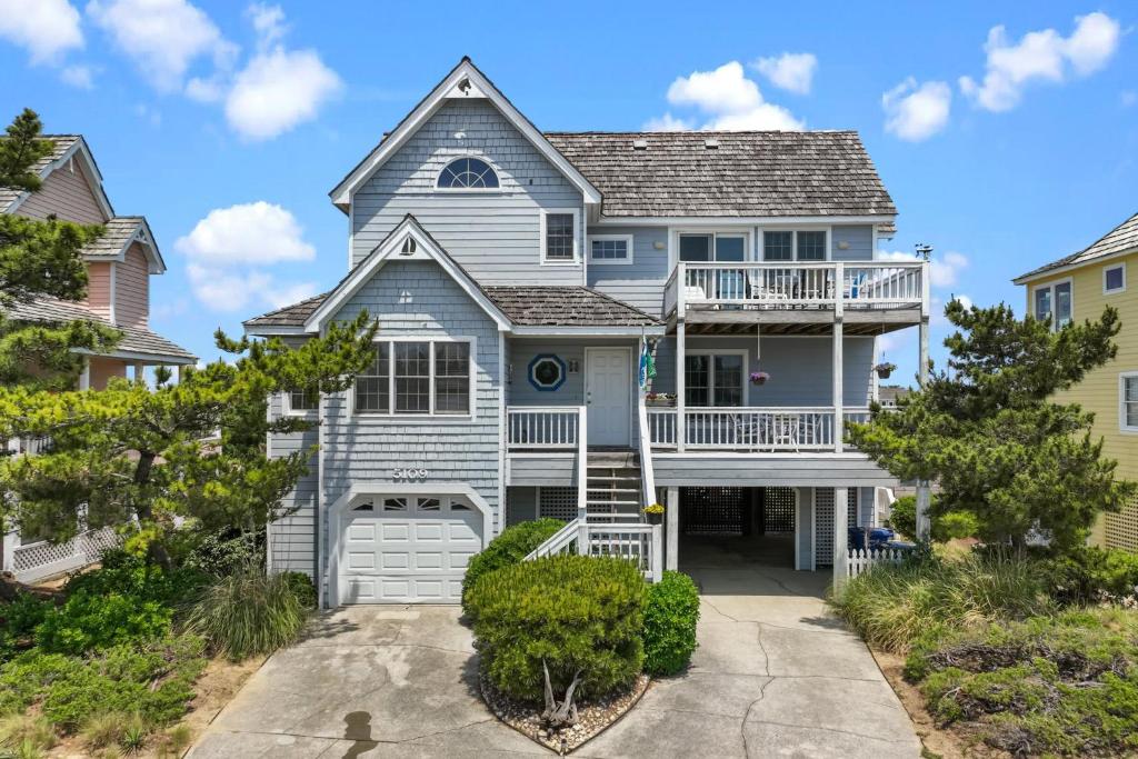 a blue house with a balcony and a driveway at 5592 - Windjammer in Nags Head