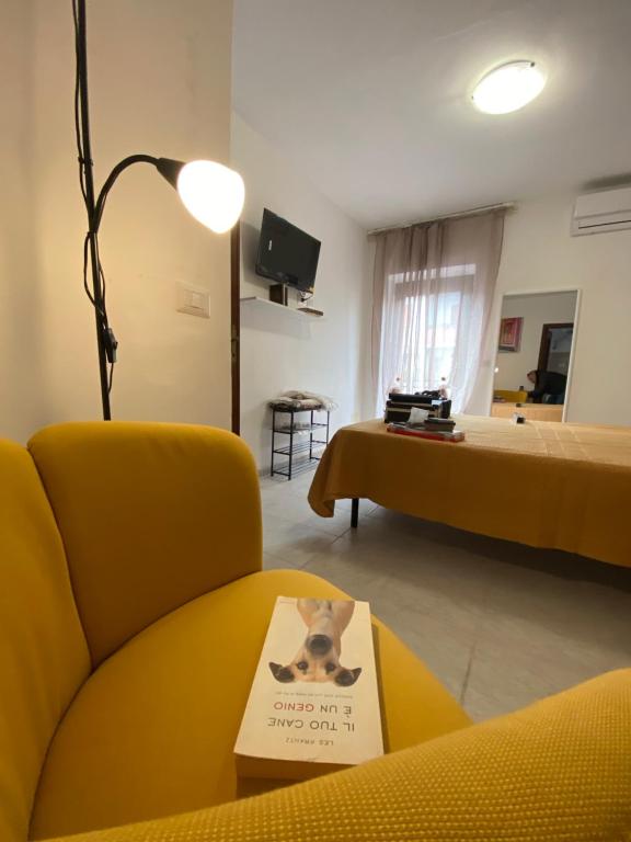 a living room with a yellow chair and a book on a table at La Casa di Siria in Bomarzo