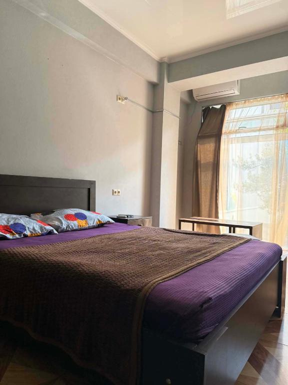 a bedroom with a bed with purple sheets and a window at Saburtalo Central in Tbilisi City