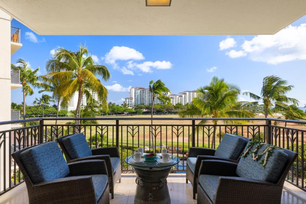 a balcony with chairs and a table and palm trees at Ko Olina Beach Villas B403 in Kapolei