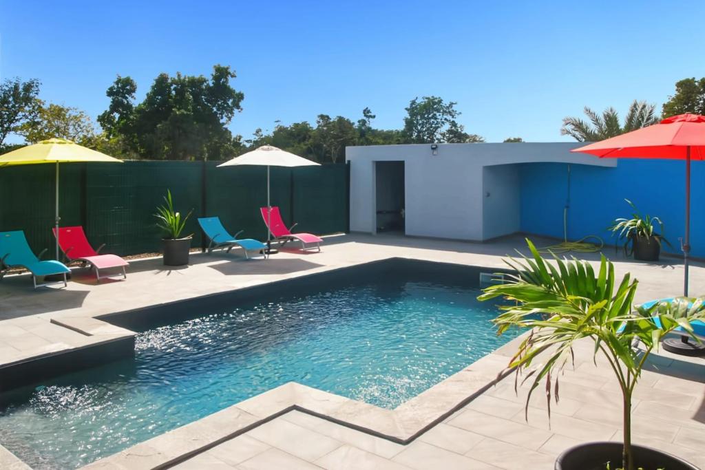 a pool with chairs and umbrellas on a patio at Villa Sibaloma in Saint-François