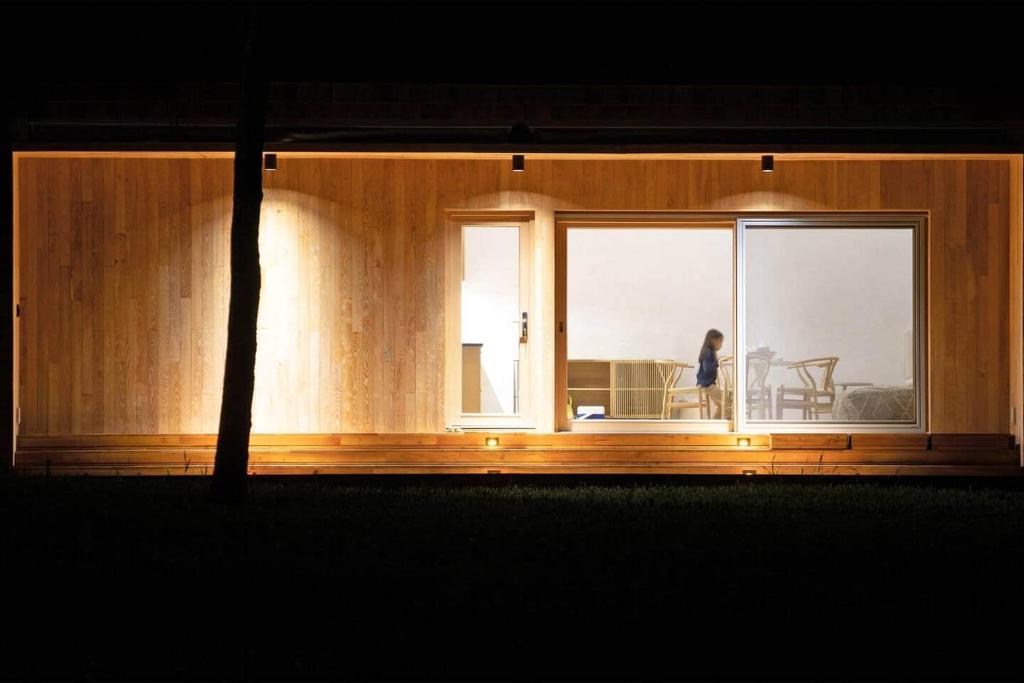 a woman sitting on a couch looking out of a window at Architectural Cabin 18 mins to Catamount in Taghkanic