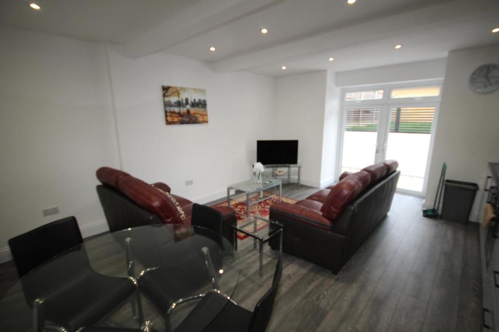 a living room with two couches and a glass table at Osterley Place - Apt A in Hounslow