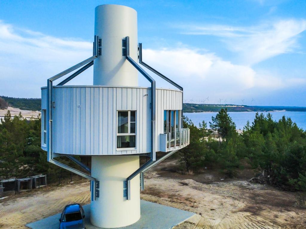 a house on top of a lighthouse next to the water at NORA Turmhaus am Bergheider See in Buschmühle