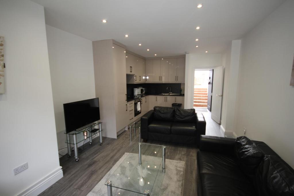 a living room with a black couch and a kitchen at Osterley Place - Apt F in Hounslow