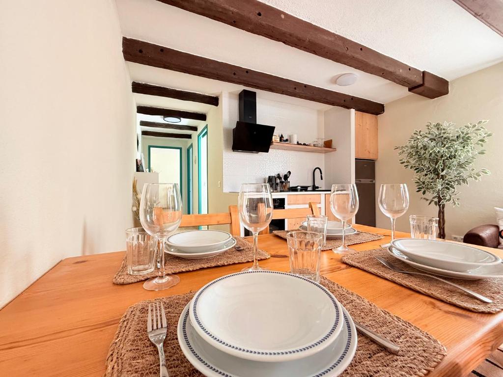 a wooden table with plates and wine glasses on it at Casa Maya by GMHouse Menorca in Cala Blanca