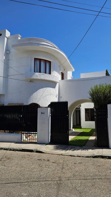 ein weißes Haus mit schwarzem Zaun und einem Kühlschrank in der Unterkunft Wanderlust Hostel B & B in Santiago