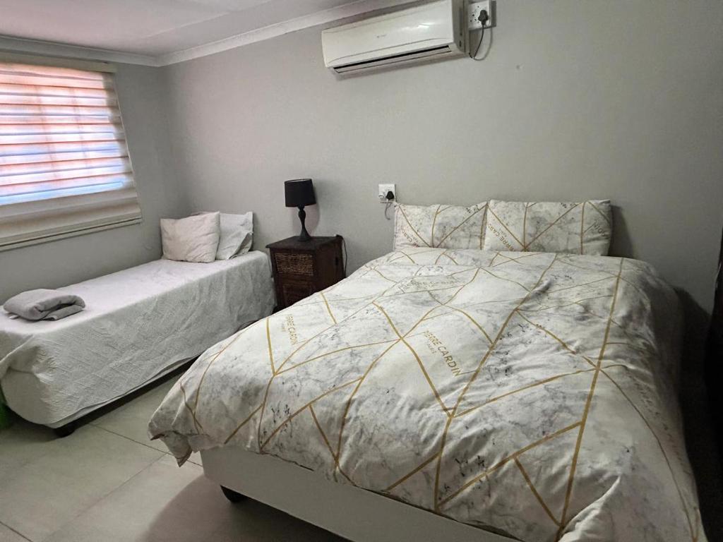 a bedroom with a bed and a night stand with a window at Primkop Cottage in White River
