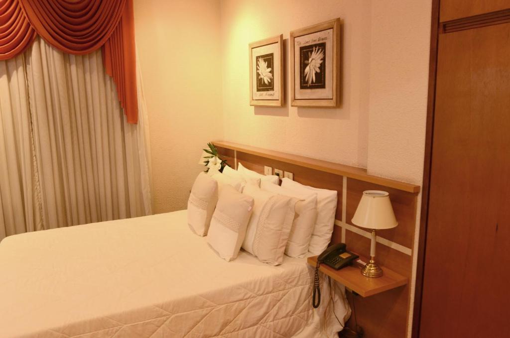 a hotel room with a bed with white pillows at Skalla Hotel Nova Odessa in Nova Odessa