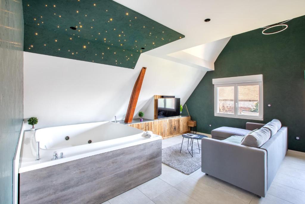 a large bathroom with a large tub and a couch at Gite Spa L'Atelier Emile - Spa Privatif - 5 min COLMAR in Sainte-Croix-en-Plaine