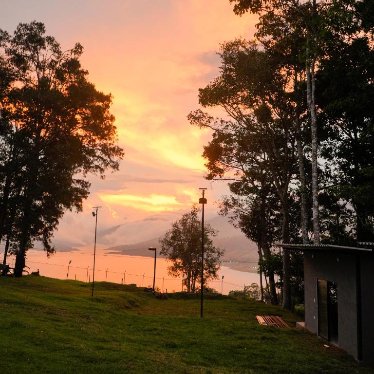 a sunset in a field with trees and lights at Valle de las Bendiciones, Lago Calima in Calima
