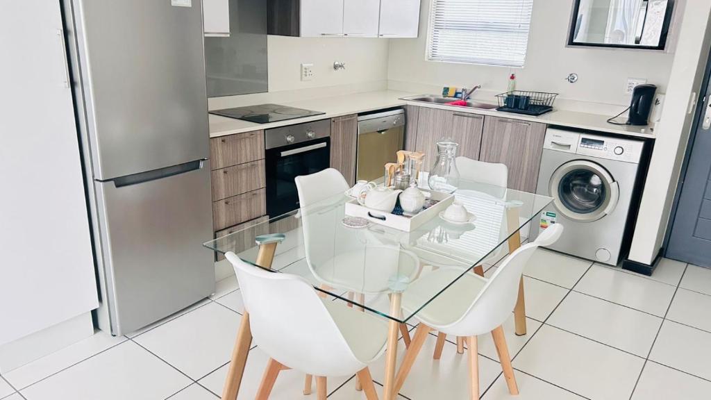 a kitchen with a glass table and white chairs at Luxury Fourways Apartment, Pool, Gym and 24hr Security - Ventura Estate in Sandton