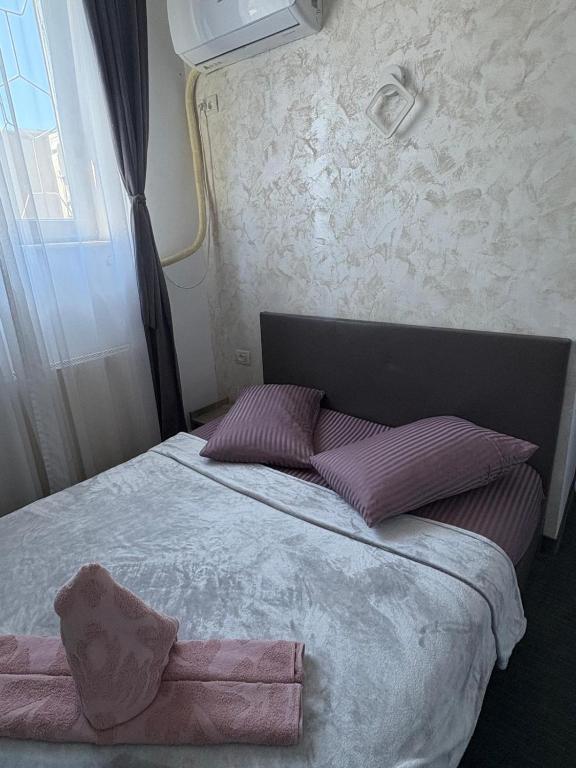 a bedroom with a bed with purple pillows and a window at Wednesday House in Constanţa