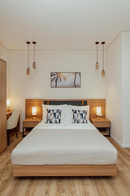 a bedroom with a large bed with two tables and two lamps at Hotel ORJEN sport & pleasure in Trebinje