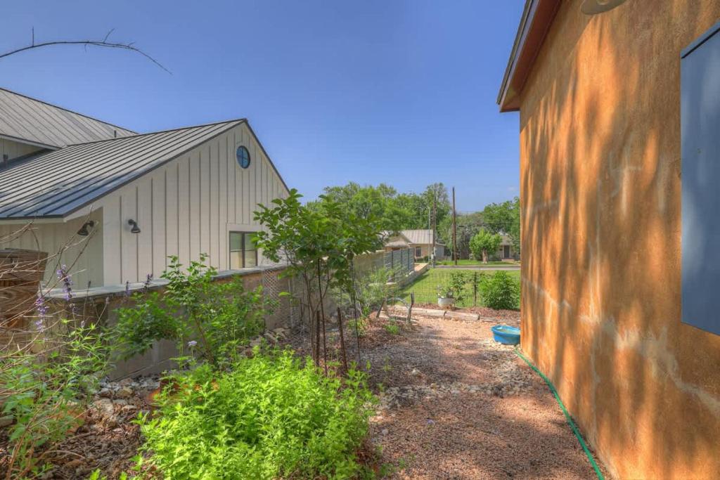 a house with a fence next to a building at Tejas Suite Walking Distance to Main St! in Fredericksburg